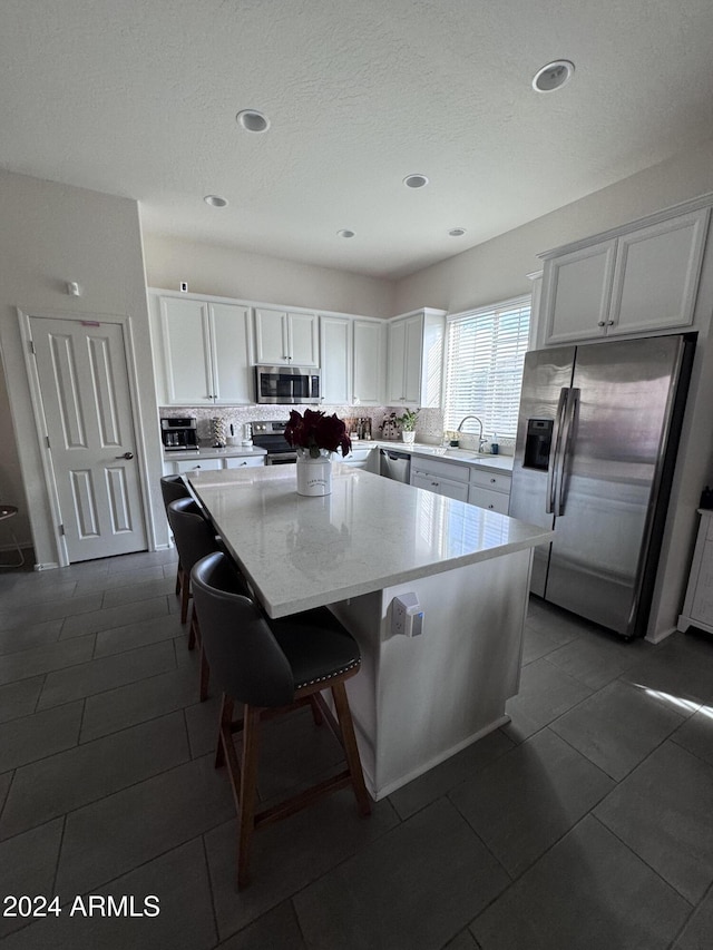 kitchen with a center island, white cabinets, a kitchen breakfast bar, sink, and stainless steel appliances