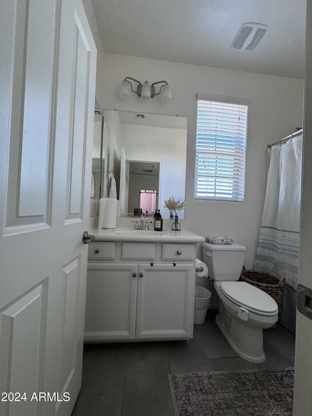 bathroom featuring tile patterned floors, vanity, toilet, and walk in shower