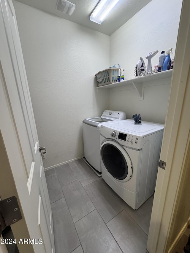 laundry area featuring washer and dryer and light tile patterned floors