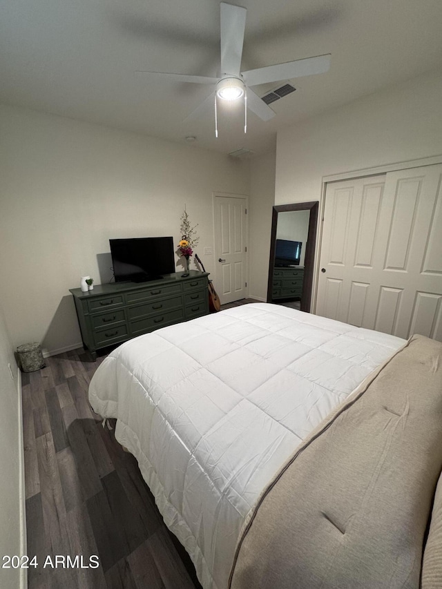 bedroom with ceiling fan, dark wood-type flooring, and a closet