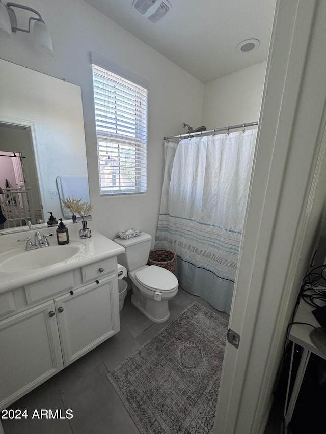 bathroom featuring toilet, vanity, tile patterned floors, and curtained shower