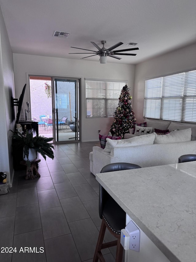 living room featuring ceiling fan and dark tile patterned flooring