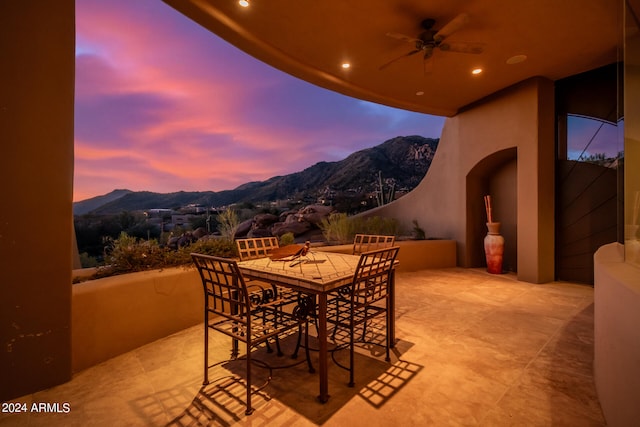 patio terrace at dusk with ceiling fan and a mountain view