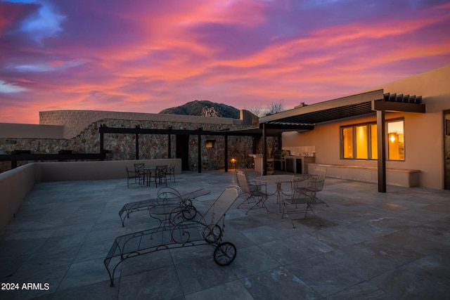 back house at dusk featuring a patio