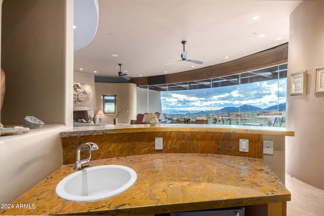 interior space featuring ceiling fan, sink, light stone counters, and a mountain view