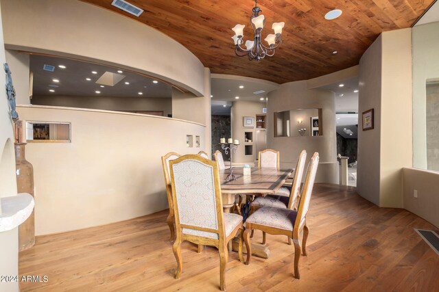 dining area with lofted ceiling, light wood-type flooring, wood ceiling, and an inviting chandelier