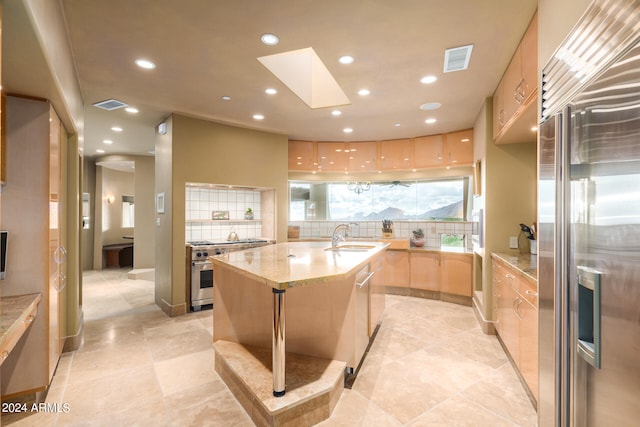 kitchen featuring a center island with sink, tasteful backsplash, light tile flooring, and high quality appliances