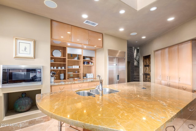 kitchen featuring a fireplace, built in refrigerator, light tile floors, and sink