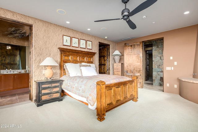 bedroom featuring light carpet, ensuite bath, and ceiling fan