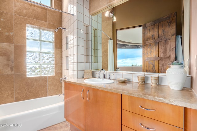 bathroom with tiled shower / bath combo, large vanity, and a healthy amount of sunlight