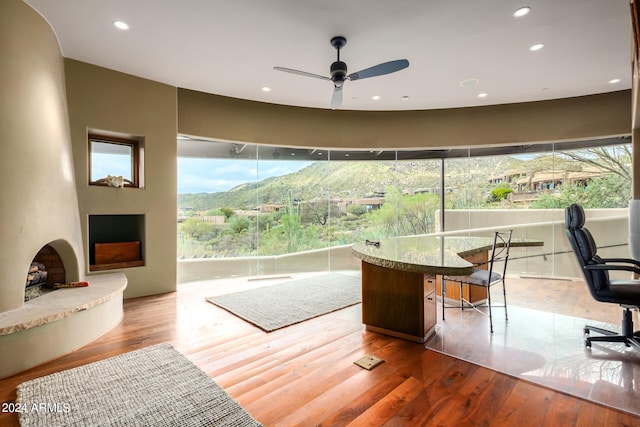 office space featuring a large fireplace, ceiling fan, a healthy amount of sunlight, and light hardwood / wood-style flooring