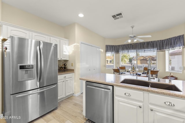 kitchen with white cabinetry, appliances with stainless steel finishes, sink, and light stone counters