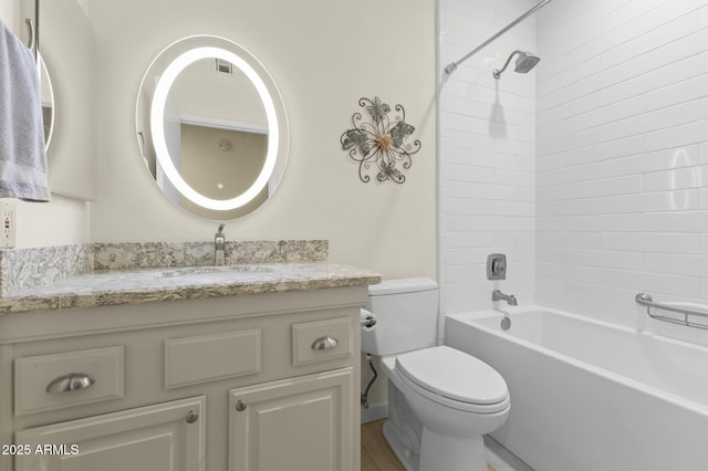 full bathroom featuring vanity, tiled shower / bath combo, and toilet