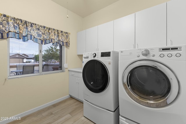 washroom with light hardwood / wood-style flooring, washing machine and dryer, and cabinets