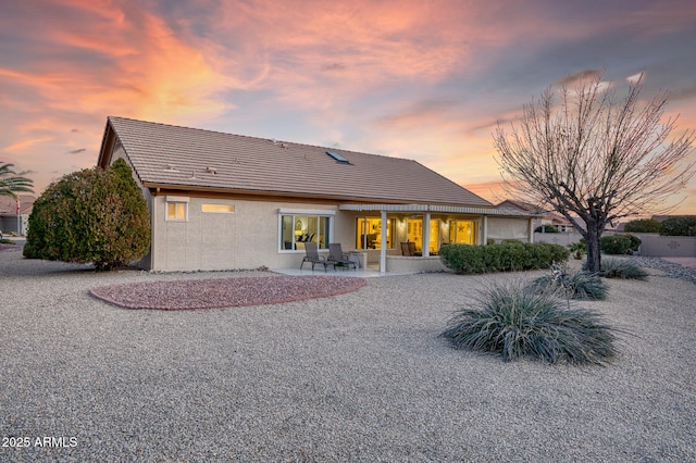 back house at dusk featuring a patio