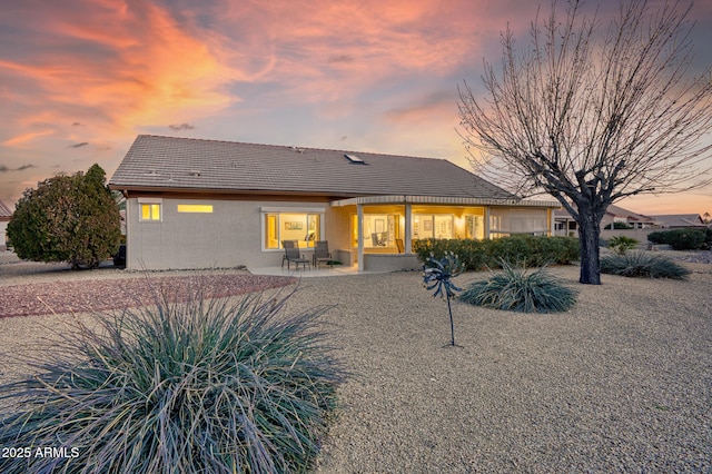 back house at dusk with a patio area