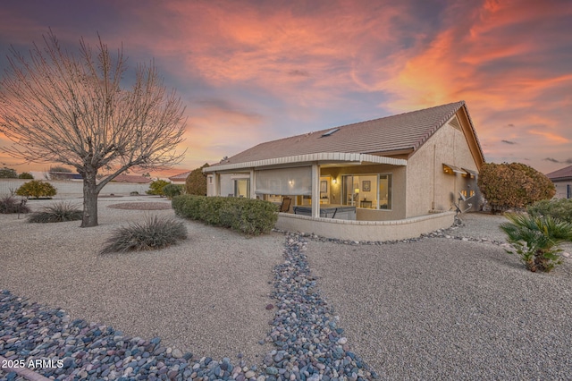 back house at dusk featuring a patio area