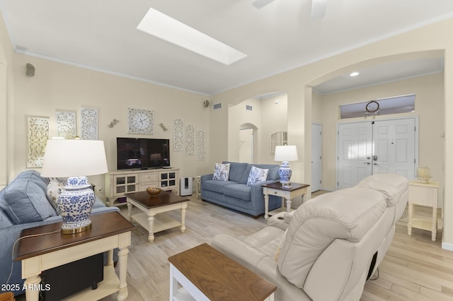 living room with ornamental molding, light hardwood / wood-style floors, and a skylight