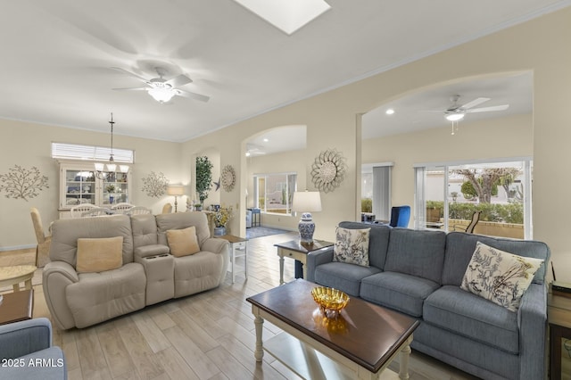 living room with crown molding, ceiling fan with notable chandelier, and light hardwood / wood-style flooring