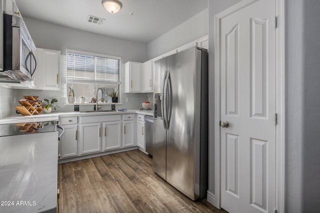 kitchen featuring backsplash, light stone countertops, white cabinetry, and appliances with stainless steel finishes