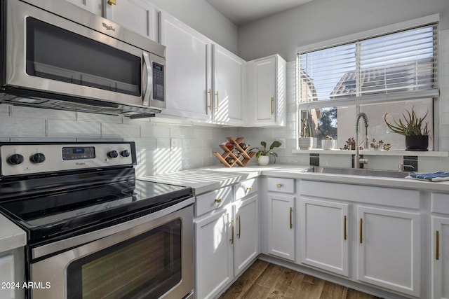 kitchen with dark hardwood / wood-style floors, stainless steel appliances, white cabinetry, and sink