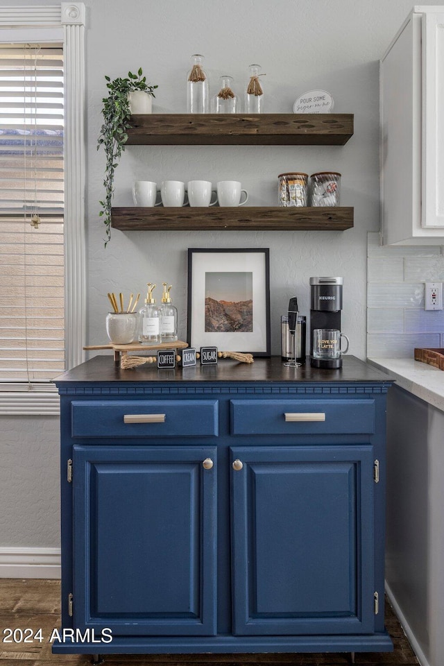 bar featuring tasteful backsplash, white cabinets, dark wood-type flooring, and blue cabinetry