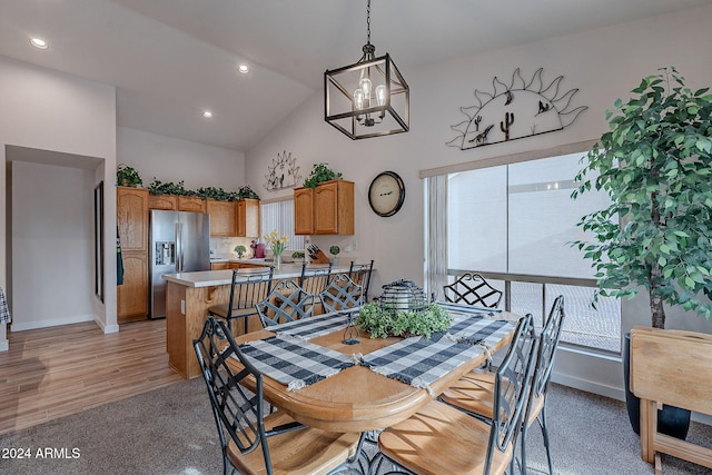 dining area featuring a notable chandelier, light hardwood / wood-style floors, and high vaulted ceiling