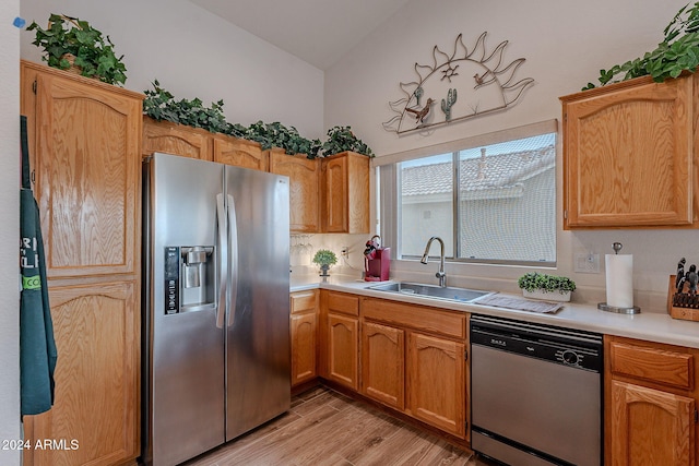 kitchen featuring tasteful backsplash, stainless steel appliances, vaulted ceiling, sink, and light hardwood / wood-style floors