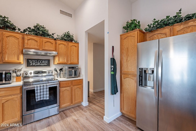 kitchen featuring appliances with stainless steel finishes, high vaulted ceiling, and light hardwood / wood-style flooring