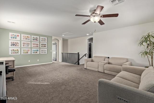 carpeted living area with visible vents, arched walkways, and ceiling fan