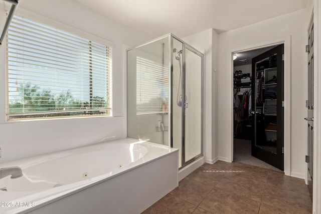 full bathroom featuring a shower stall, a spacious closet, a tub with jets, and tile patterned flooring