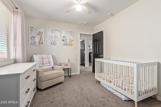 bedroom with visible vents, light carpet, ceiling fan, a crib, and baseboards