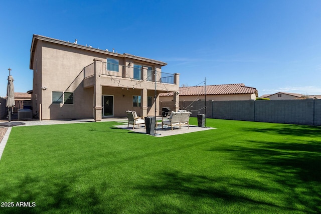 rear view of house featuring a patio area, a lawn, fence, and stucco siding