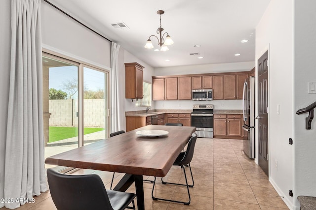 kitchen featuring light tile patterned flooring, a notable chandelier, stainless steel appliances, visible vents, and pendant lighting