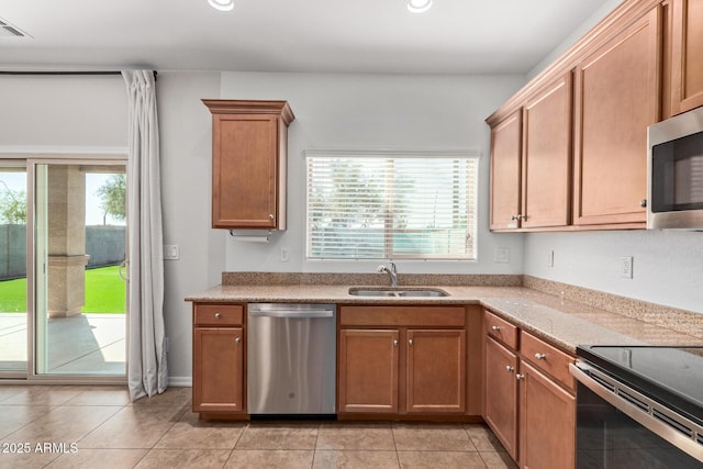 kitchen with brown cabinets, stainless steel appliances, a sink, and recessed lighting