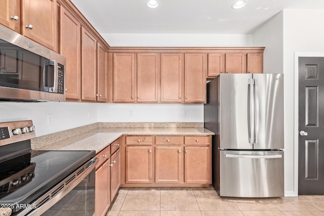 kitchen with light stone countertops, light tile patterned floors, appliances with stainless steel finishes, and recessed lighting