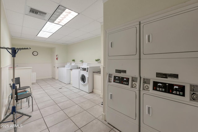 shared laundry area with washer and clothes dryer, visible vents, stacked washer and clothes dryer, and light tile patterned floors