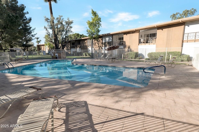 community pool with a patio and fence