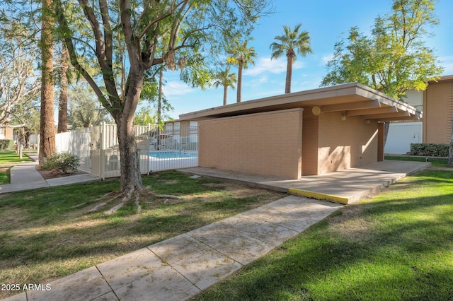 exterior space featuring a patio area, a swimming pool, fence, and a lawn