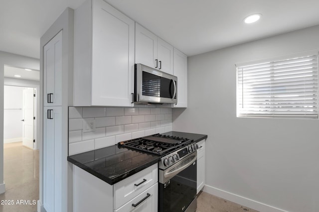 kitchen with stainless steel appliances, baseboards, dark countertops, and decorative backsplash