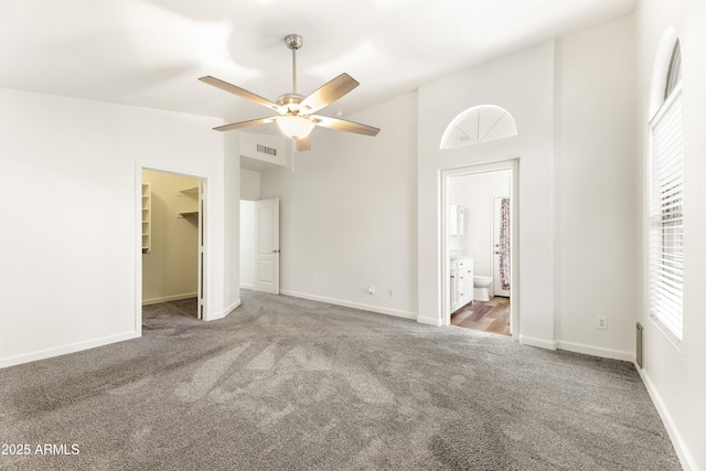 unfurnished bedroom with a spacious closet, visible vents, baseboards, vaulted ceiling, and carpet flooring