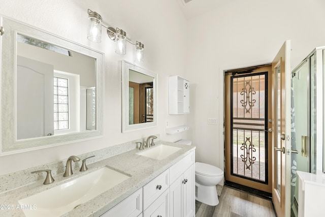 full bathroom with toilet, wood finished floors, a stall shower, and a sink