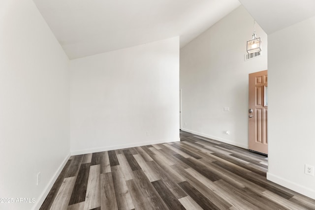 spare room featuring baseboards, high vaulted ceiling, and wood finished floors