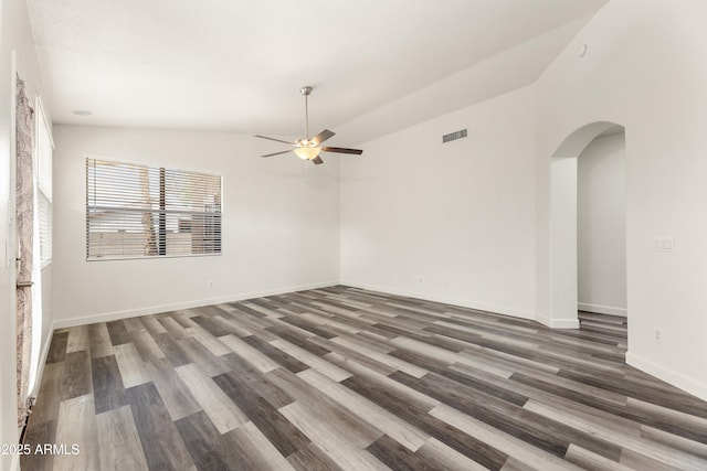 unfurnished room with visible vents, arched walkways, wood finished floors, and a ceiling fan