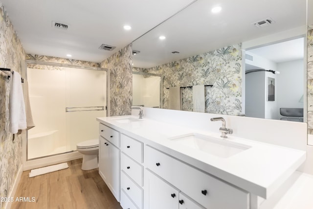 bathroom with vanity, hardwood / wood-style flooring, a shower with door, and toilet