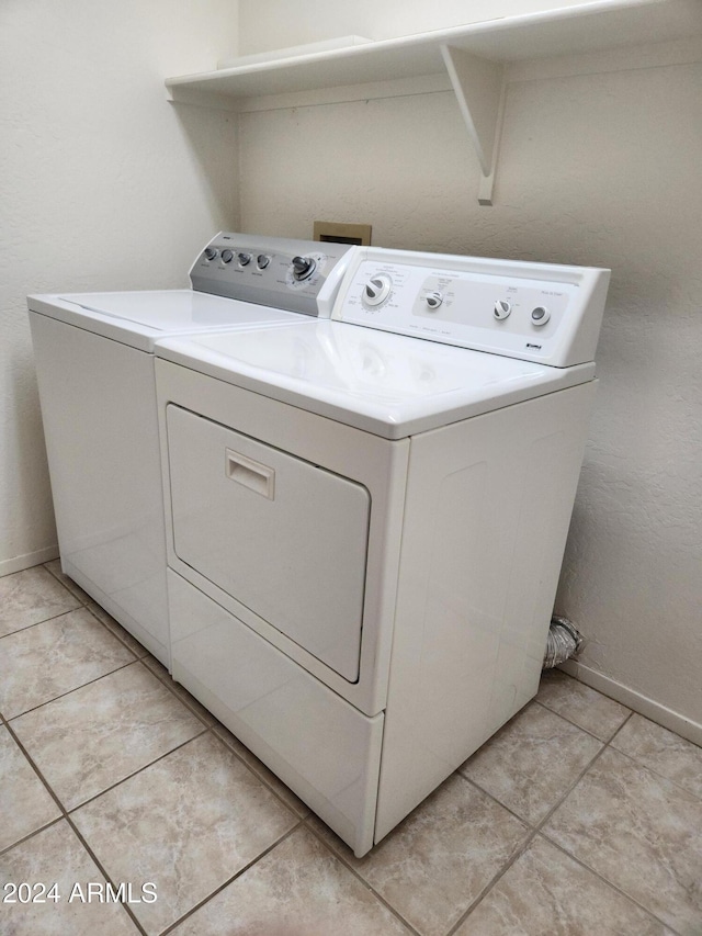 clothes washing area featuring washing machine and clothes dryer and light tile patterned floors