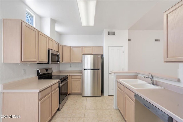 kitchen with appliances with stainless steel finishes, light brown cabinets, light tile patterned floors, and sink