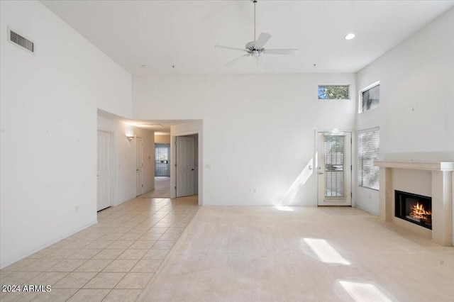 unfurnished living room with ceiling fan, light tile patterned floors, and a high ceiling