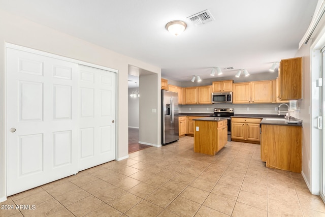 kitchen with appliances with stainless steel finishes, a center island, light tile patterned floors, and sink