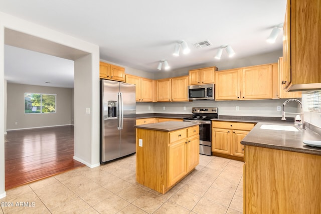 kitchen with light hardwood / wood-style floors, a kitchen island, stainless steel appliances, light brown cabinetry, and sink